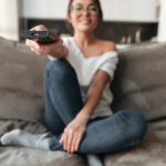 happy-young-woman-sitting-sofa-home-watch-tv